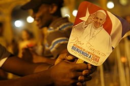 Young Catholic faithful holds a sign reads: 'Welcome Pope Francis' during a vigil to pray in front of Havana's Cathedral in Havana September 18, 2015. The Obama administration announced wide-ranging new rules on Friday to ease trade, travel and investment restrictions with Cuba, the latest effort to chip away at the long-standing U.S. economic embargo amid a diplomatic thaw between the two former Cold War foes.The announcement came just as Pope Francis, who played an instrumental role in the diplomatic opening late last year, prepares to visit Cuba this weekend before heading to the United State next week. The Vatican has long condemned the embargo against Cuba. REUTERS/Carlos GarciaRawlins